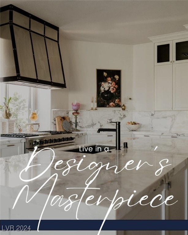 kitchen featuring light stone counters, white cabinetry, and high end range