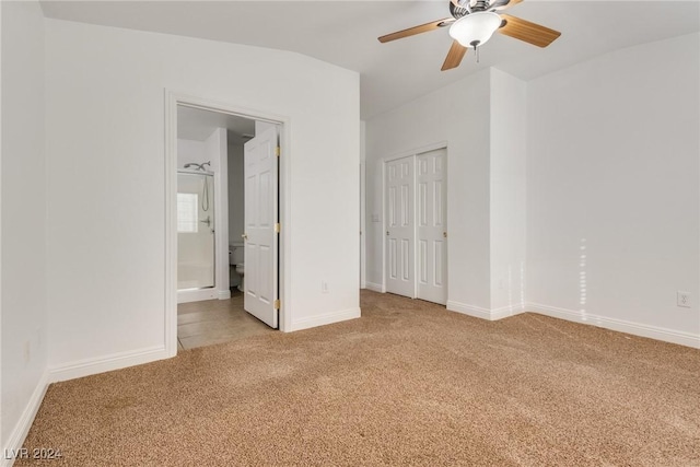 unfurnished bedroom with connected bathroom, light carpet, ceiling fan, and lofted ceiling