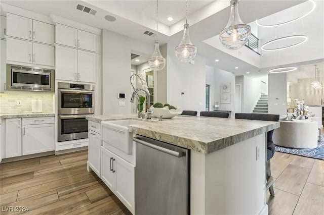 kitchen with white cabinets, sink, a center island with sink, and stainless steel appliances