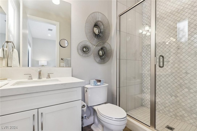 bathroom featuring vanity, toilet, and a shower with shower door