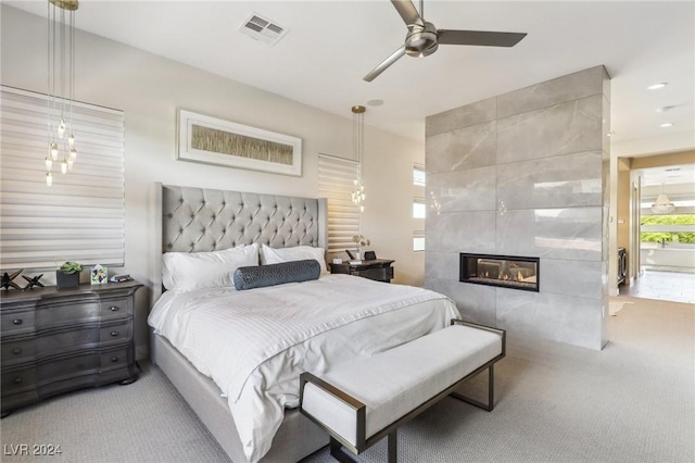 bedroom with ceiling fan, light carpet, and a tile fireplace