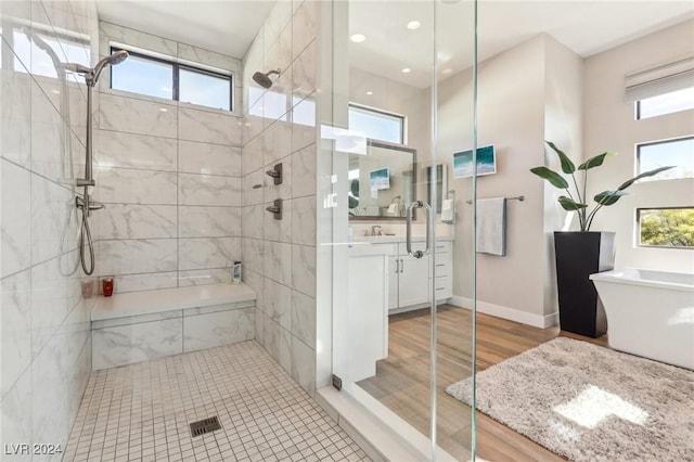 bathroom with hardwood / wood-style floors, independent shower and bath, and a wealth of natural light