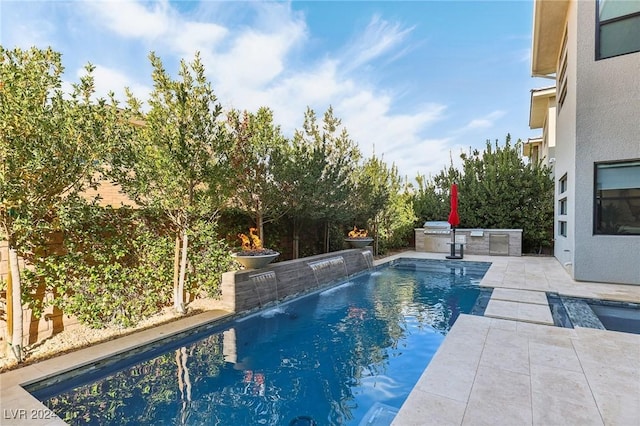 view of swimming pool featuring pool water feature, a patio, and exterior kitchen