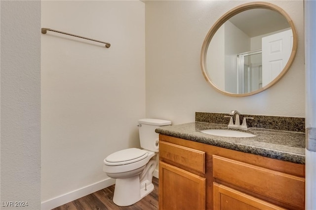 bathroom with hardwood / wood-style floors, vanity, an enclosed shower, and toilet