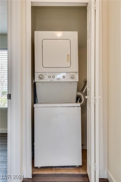 clothes washing area with dark hardwood / wood-style floors and stacked washing maching and dryer