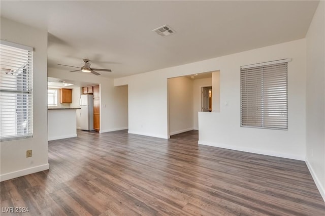 unfurnished living room featuring ceiling fan and dark wood-type flooring