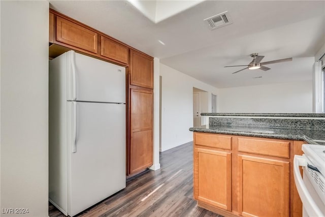 kitchen with white appliances, dark hardwood / wood-style floors, ceiling fan, and dark stone counters