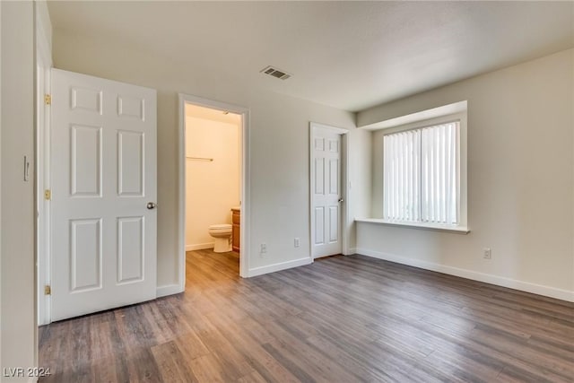 unfurnished bedroom featuring connected bathroom and dark wood-type flooring