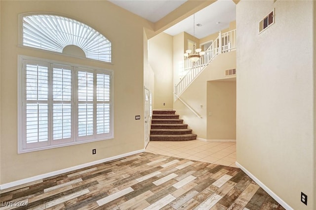 foyer entrance featuring a high ceiling, hardwood / wood-style flooring, and a notable chandelier