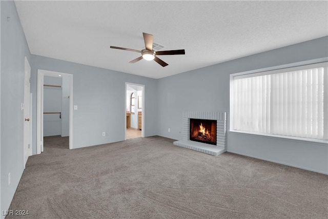 unfurnished living room with ceiling fan, light colored carpet, and a brick fireplace