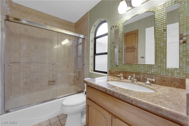 full bathroom featuring tile patterned flooring, vanity, bath / shower combo with glass door, and toilet