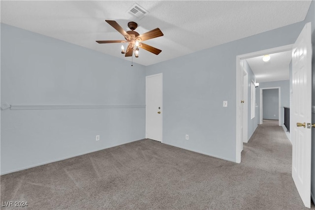 unfurnished room featuring ceiling fan, light colored carpet, and a textured ceiling