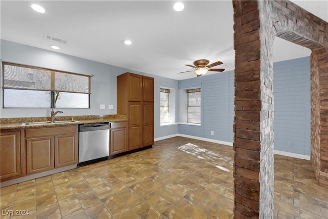 kitchen featuring ceiling fan, dishwasher, light stone counters, and sink