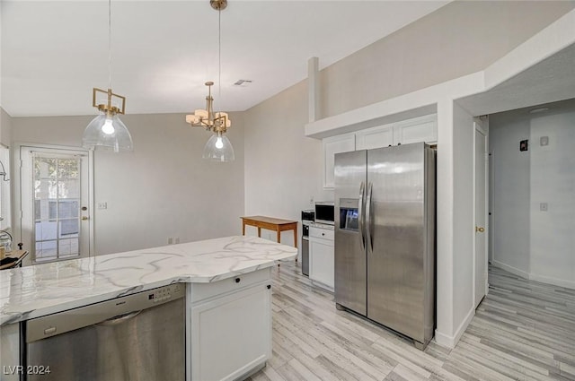 kitchen with white cabinets, hanging light fixtures, vaulted ceiling, light stone countertops, and stainless steel appliances