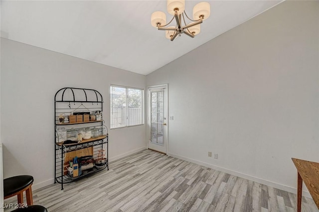 spare room with light hardwood / wood-style floors, lofted ceiling, and a notable chandelier