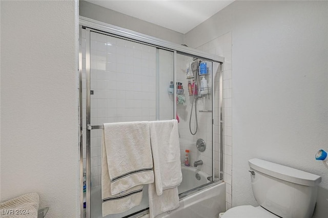 bathroom featuring bath / shower combo with glass door and toilet