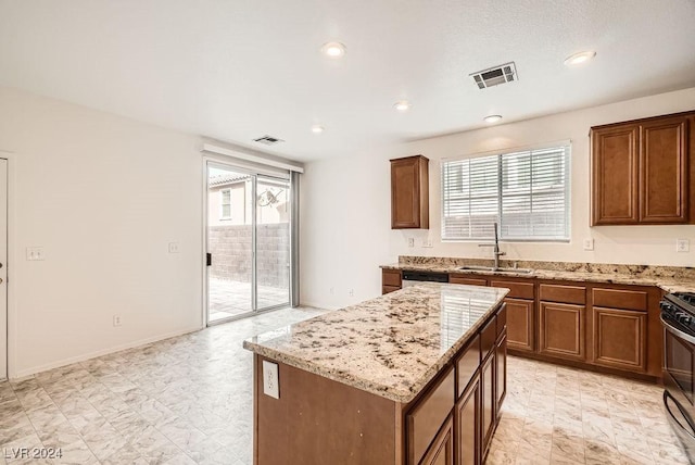 kitchen featuring light stone countertops, a center island, sink, stainless steel dishwasher, and black gas stove