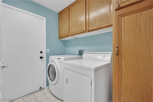 laundry room featuring cabinets, light tile patterned floors, and washing machine and clothes dryer