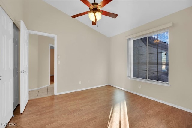 empty room with ceiling fan, vaulted ceiling, and light hardwood / wood-style flooring