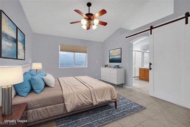 tiled bedroom featuring ceiling fan, a barn door, lofted ceiling, and connected bathroom