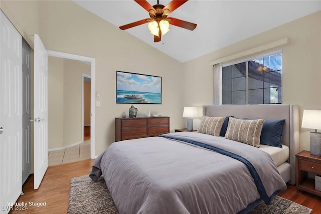 bedroom with a closet, ceiling fan, hardwood / wood-style floors, and lofted ceiling