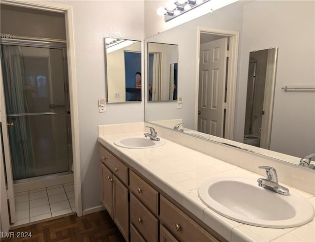 bathroom featuring parquet flooring, vanity, toilet, and a shower with shower door