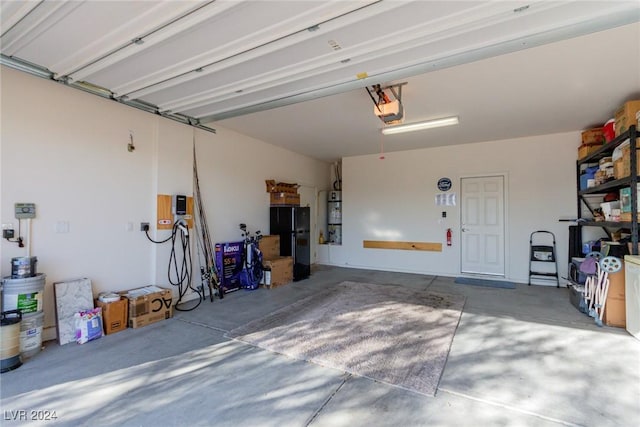 garage featuring a garage door opener, black fridge, and water heater