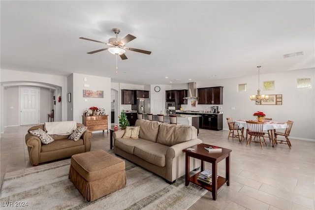 tiled living room with ceiling fan with notable chandelier