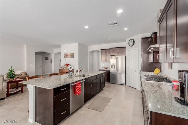 kitchen with light stone countertops, sink, an island with sink, and stainless steel appliances