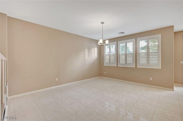 empty room with light tile patterned floors and a chandelier