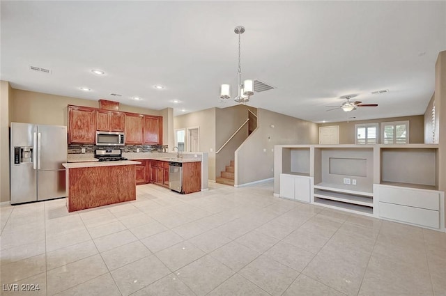 kitchen featuring ceiling fan with notable chandelier, light tile patterned floors, appliances with stainless steel finishes, decorative light fixtures, and a kitchen island