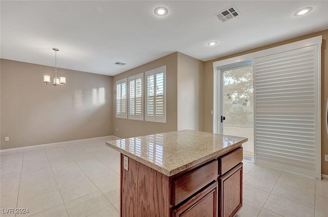 kitchen with pendant lighting, a center island, light stone countertops, a wealth of natural light, and a notable chandelier