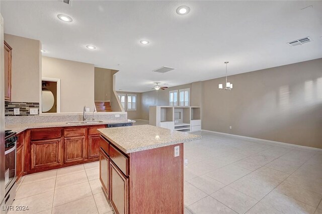 kitchen with decorative backsplash, appliances with stainless steel finishes, ceiling fan with notable chandelier, sink, and a kitchen island