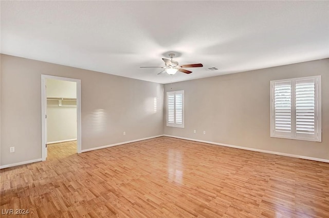 unfurnished bedroom with a closet, light hardwood / wood-style floors, a spacious closet, and ceiling fan