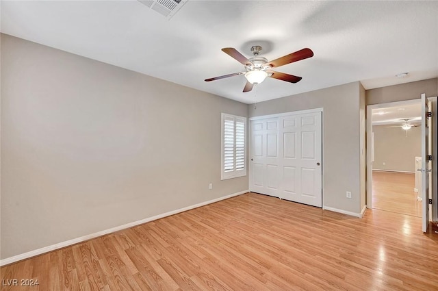 unfurnished bedroom with ceiling fan, light wood-type flooring, and a closet