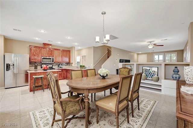 tiled dining area featuring ceiling fan with notable chandelier and sink