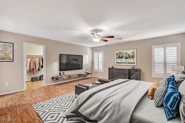 bedroom featuring light wood-type flooring, a closet, a spacious closet, and ceiling fan