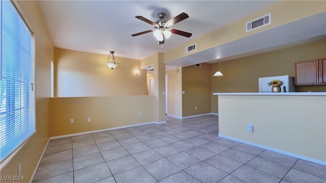 empty room featuring a ceiling fan, healthy amount of natural light, light tile patterned floors, and baseboards