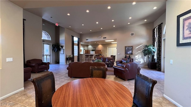dining room with a towering ceiling, recessed lighting, light tile patterned floors, and baseboards