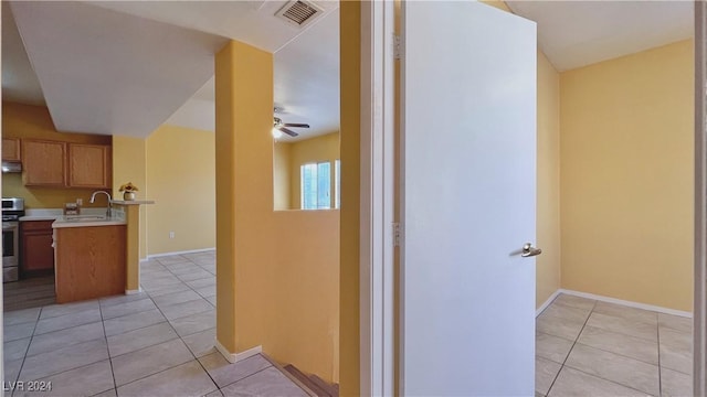 hall featuring light tile patterned flooring, a sink, and baseboards