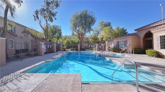 community pool featuring fence and a patio