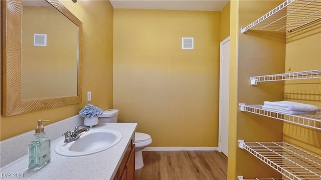 bathroom featuring wood finished floors, toilet, vanity, and baseboards