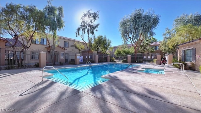 view of swimming pool featuring fence, a hot tub, a residential view, and a patio