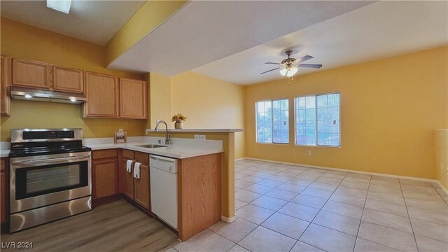 kitchen featuring electric range, under cabinet range hood, a sink, dishwasher, and a peninsula
