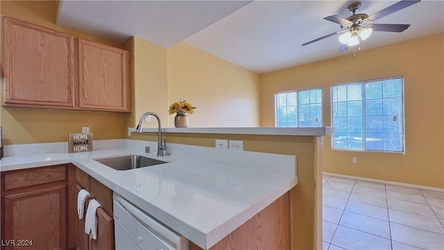 kitchen with a sink, a peninsula, dishwashing machine, light countertops, and ceiling fan