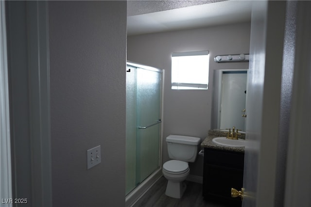 bathroom with hardwood / wood-style flooring, vanity, an enclosed shower, and toilet