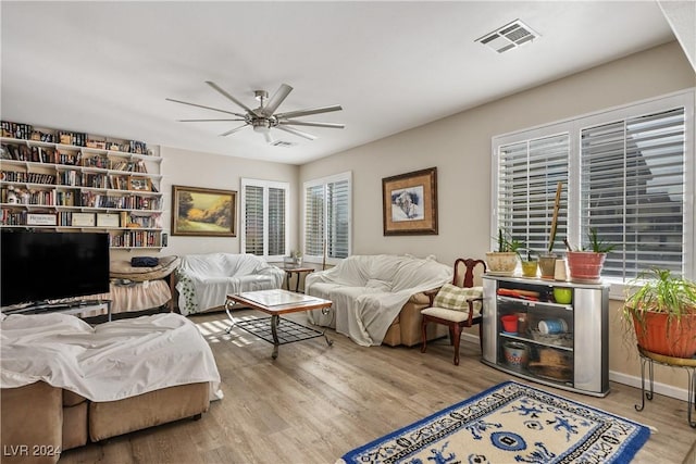 living room with a wealth of natural light, light hardwood / wood-style flooring, and ceiling fan