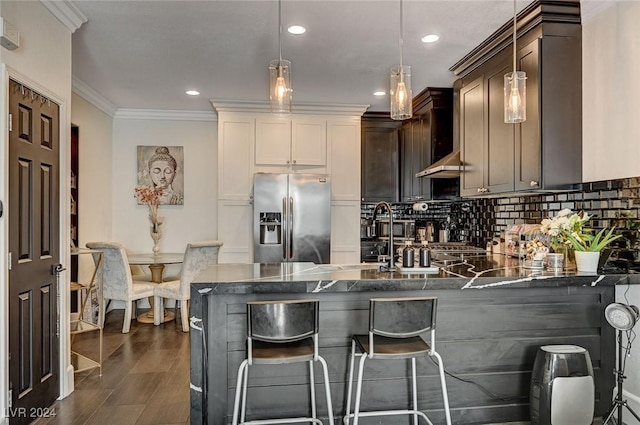 kitchen featuring pendant lighting, dark wood-type flooring, stainless steel fridge, a kitchen bar, and dark brown cabinetry