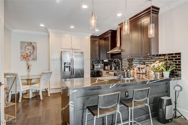 kitchen featuring kitchen peninsula, a breakfast bar, wall chimney range hood, decorative light fixtures, and stainless steel fridge with ice dispenser