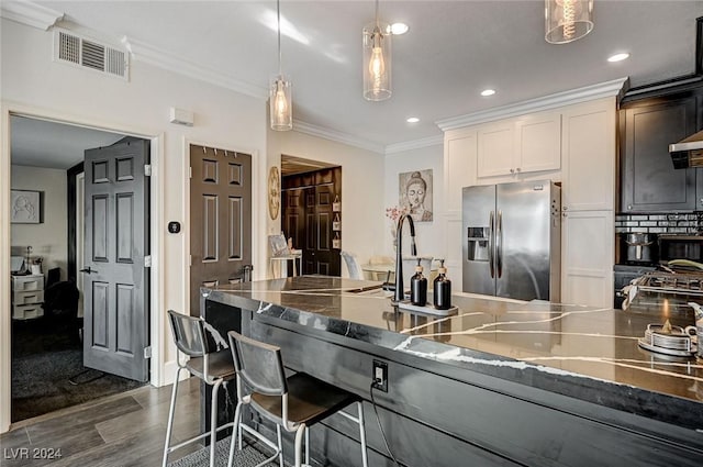 kitchen with white cabinetry, stainless steel fridge, hanging light fixtures, and ornamental molding